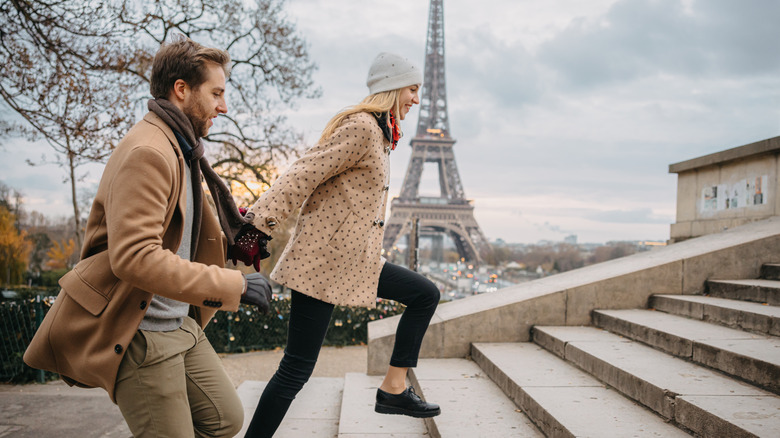Man and woman walking up stairs with Eiffel Tower in the background