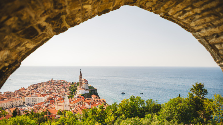 Piran, Slovenia, pictured through a stone archway, built on a peninsula jutting into the blue Mediterranean