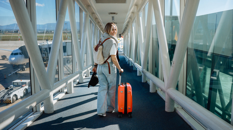 Traveler boarding airplane with a carry-on suitcase