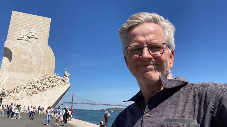 Smiling Rick Steves taking a selfie in front of an attraction in Lisbon