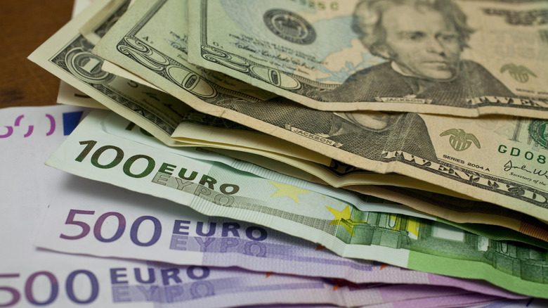 A stack of U.S. paper money on top of paper euros