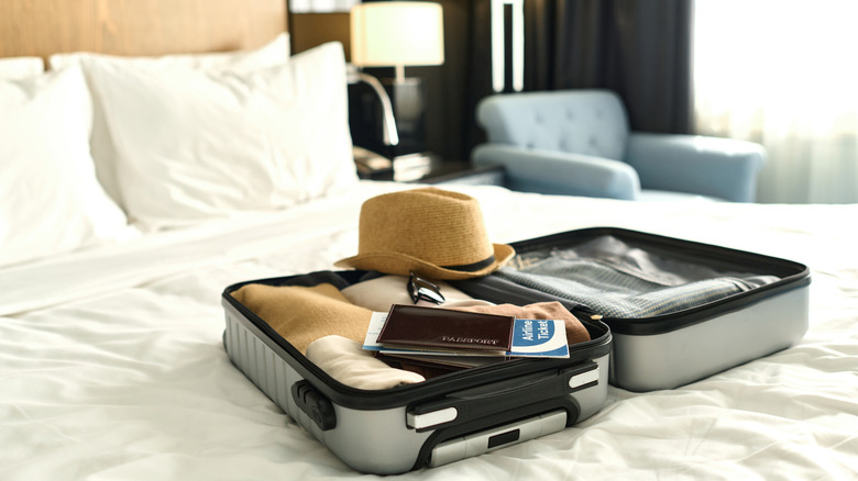 A packed case open on a bed with hat