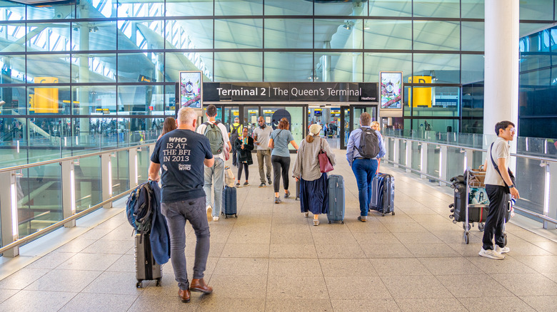 Travelers walk with suitcases into Terminal 2 at London Heathrow Airport.