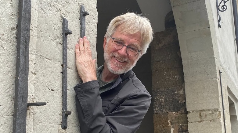 Rick Steves posing by a stone door