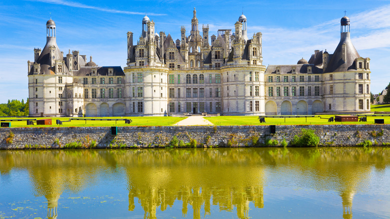 France's Château de Chambord stands reflected in a green-blue moat on a sunny day