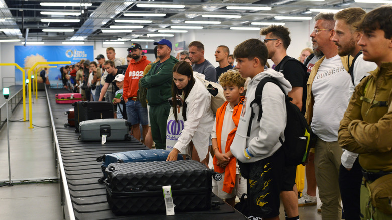 Passengers wait for their bags at the baggage carousel.