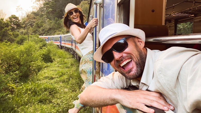 Happy excited passenger travel couple stand by doorstep enjoy popular train ride journey.