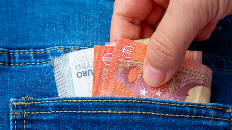 Euro bills being pulled from a jean pocket