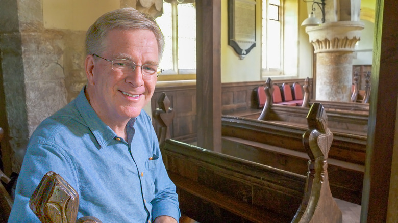 Rick Steves sitting inside the early-medieval parish church of Stanton, England.
