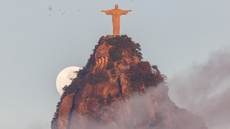 View of the Cristor Redentor statue with the moon peeking behind it