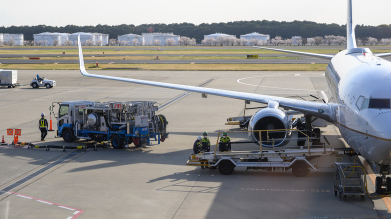 tarmac with airplane, baggage handlers, and fueling truck