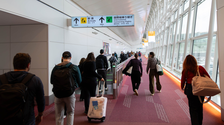 people walking down carpeted corridor inside Haneda Airport