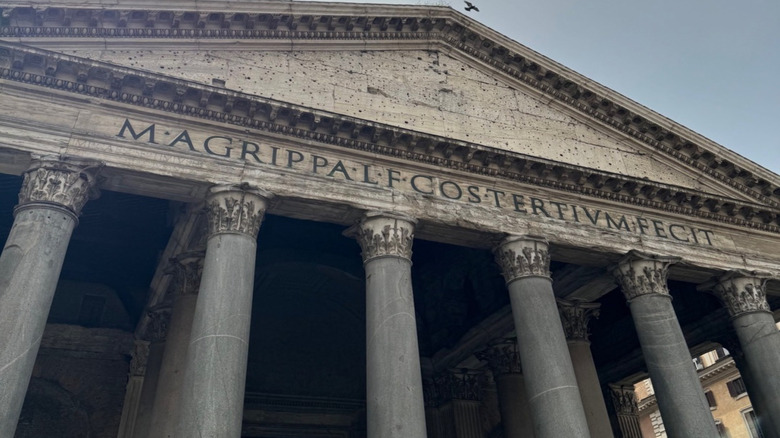 Close-up of the Roman Pantheon's nameplate and columns with a bird flying overhead