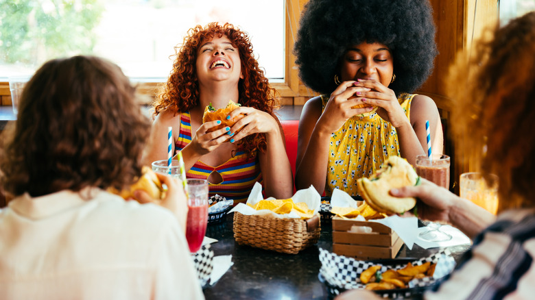 Group of friends laughing and sharing a meal at a restaurant