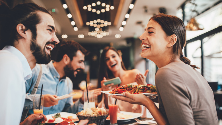 group of happy friends eating in a restaurant