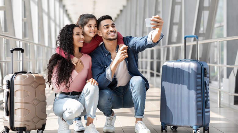 Family at the airport with luggage, squatting to pose for a picture
