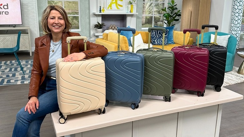 Samantha Brown sits next to a row of small, multicolored suitcases