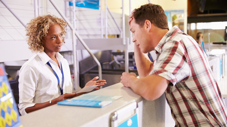 A stressed traveler checking in for his flight at an airport