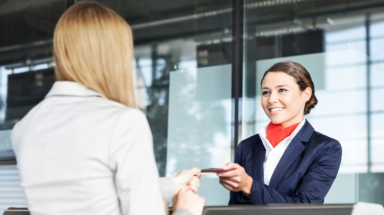 A smiling gate agent helping a traveler at an airport