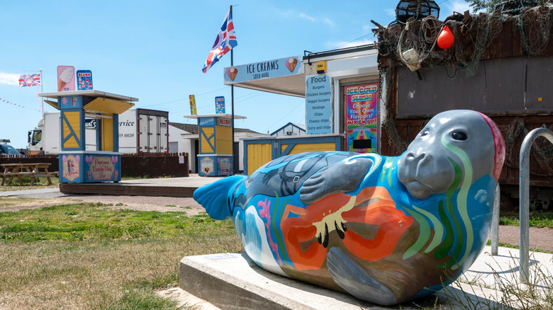 A colorful seal statue with an outdoor ice cream stand in the background