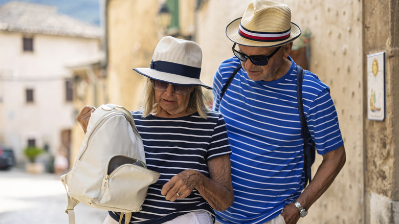A tourist couple in Italy looks concerned at their open backpack