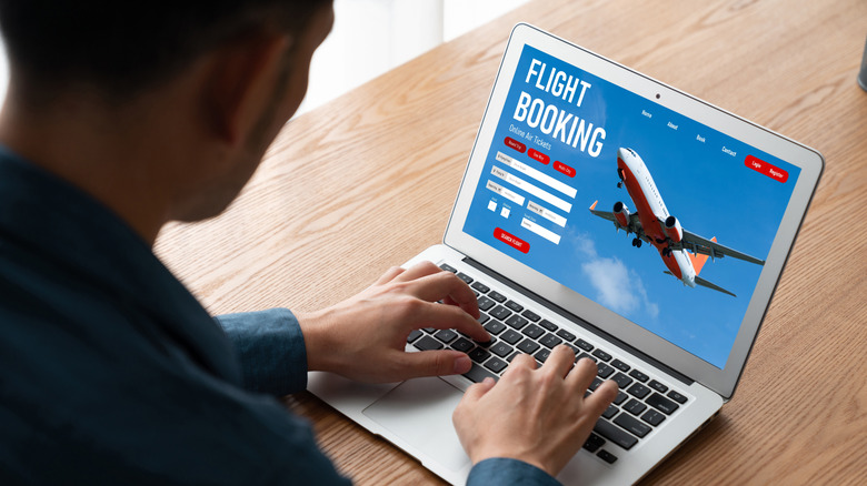 Someone booking vacation flights online using a laptop