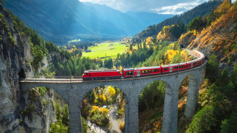 Bernina Express train over a large stone viaduct in the Swiss Alps
