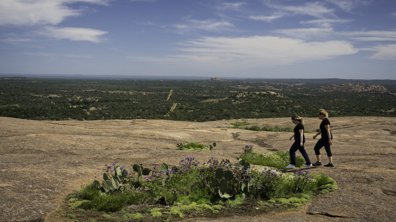 Two female hikers walk on the top of Enchanted Rock, Texas