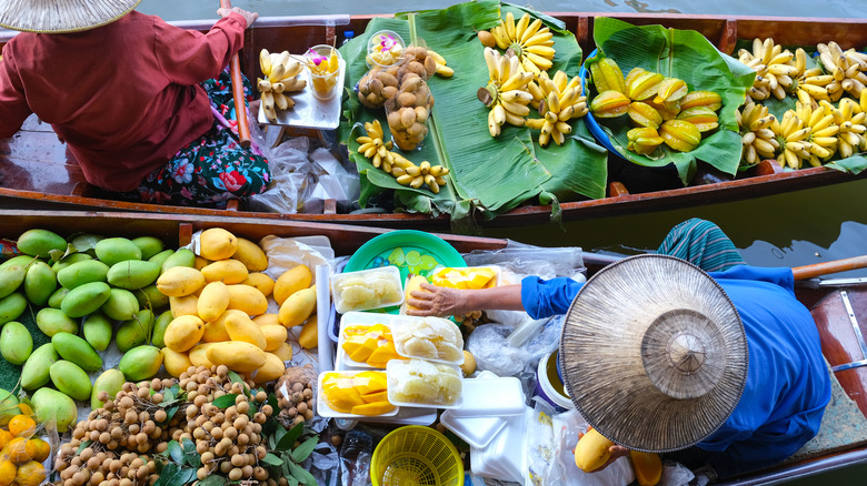 Women selling colorful fruit from their traditional boats at a floating market in Thailand