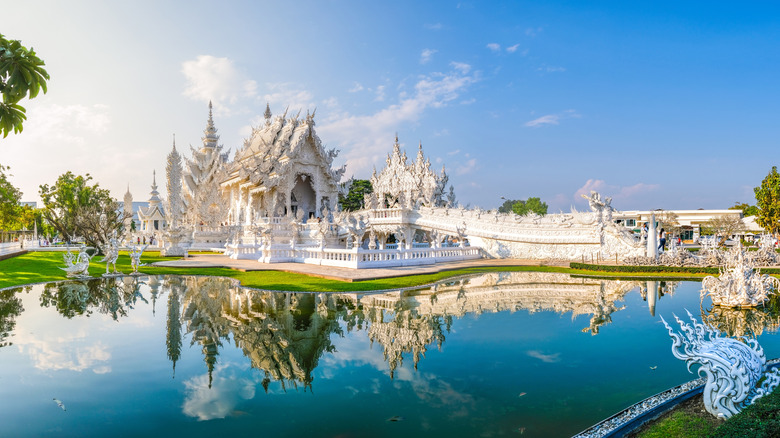 Intricate white temple reflected in a pond in Chiang Rai, Thailand