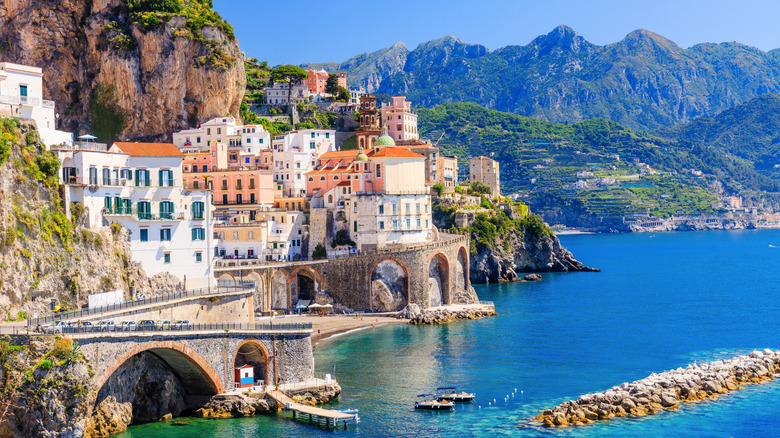 View of cliffside structures in Atrani town on Italy's Amalfi Coast, with mountains in the background and blue Mediterranean water