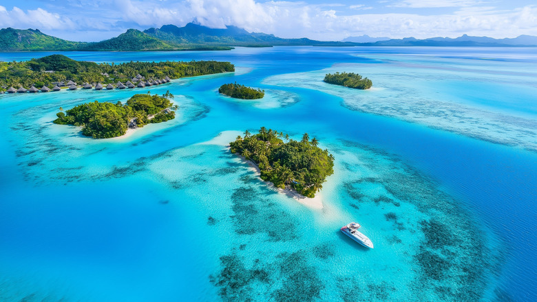 Aerial view of a tropical lagoon with turquoise water and small islands in Bora Bora, French Polynesia.