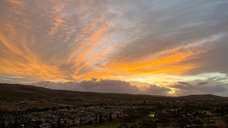 Stunning orange sunrise over Ko'Olina, Oahu, Hawaii, with lush foliage visible on the ground