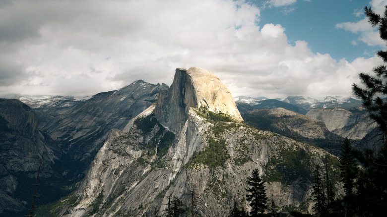 View of Half Dome from the glacier trail with puffy white clouds behind the peak