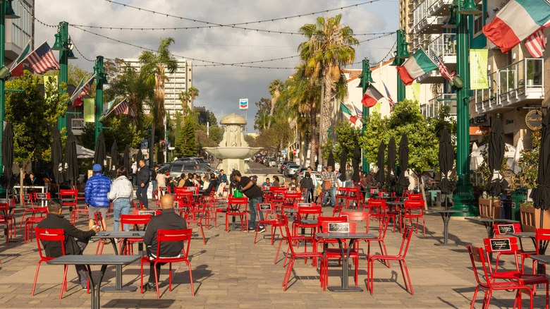 View of bright red tables and chairs and Italian flags in the Piazza della Famiglia in San Diego's Little Italy, where it serves as a community gathering spot.