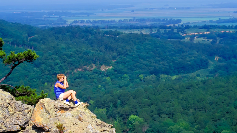 A person sits on an outcrop at Petit Jean State Park along the Scenic 7 Highway, Arkansas