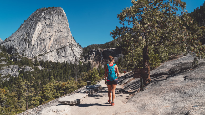 A female hiker on a path with a view of Yosemite Valley