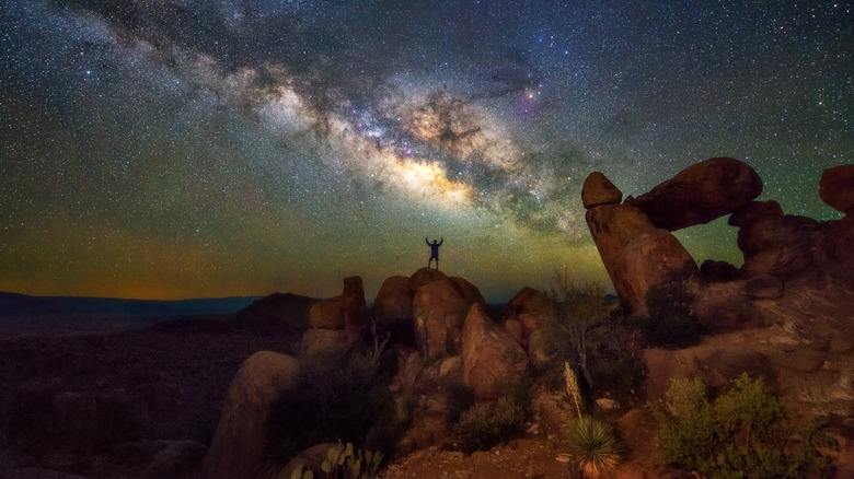 milky way in the sky above a large rock formation
