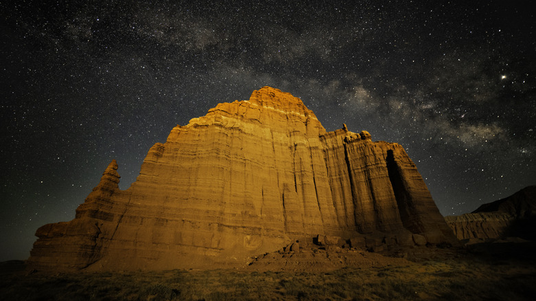 starry sky above large rock face