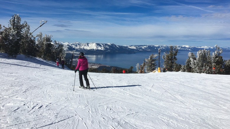 A woman skis down a slope with a view of Lake Tahoe