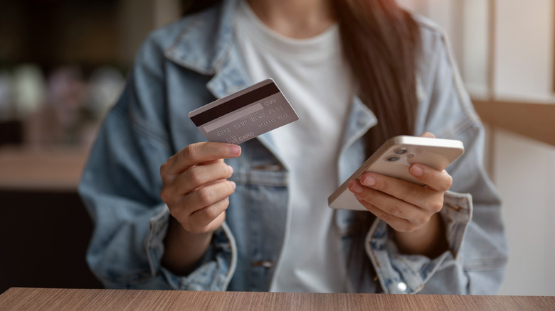 Close-up of a woman's hands holding her phone and a credit card