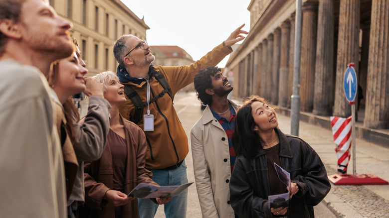 A guide points to a building and shares information with a multicultural group of tourists in Berlin