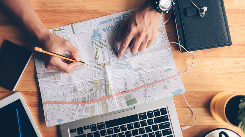 An overview of a person planning a trip using a map and computer