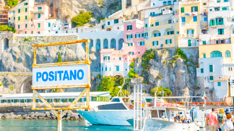 A sign in the island of Positano with colorful houses in the background