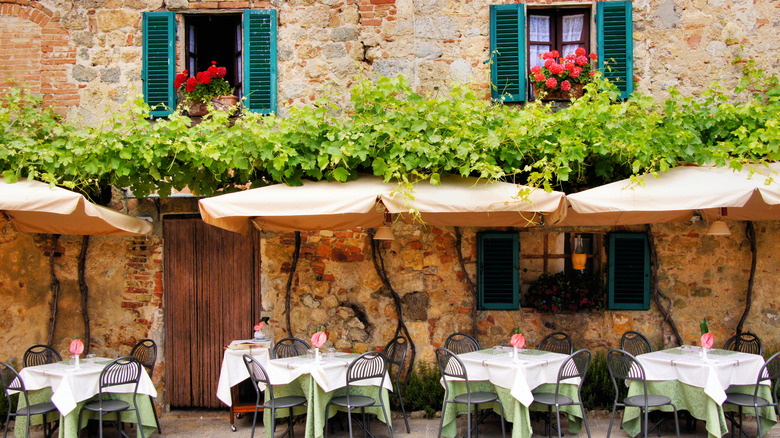 dinner chairs and tables beautifully set outside a quaint stone building