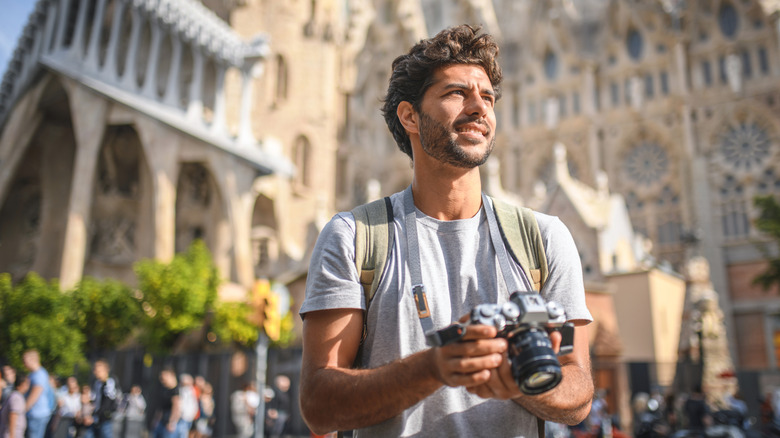 Tourist carrying an expensive camera with a church in the background