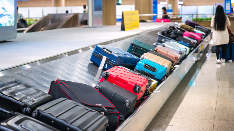 A baggage claim carousel at an airport is pictured with many colorful suitcases.