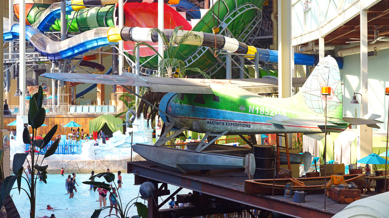 View of tube slides and theming elements, like a canoe, a byplane, and barrels at the Poconos' Aquatopia Indoor Waterpark