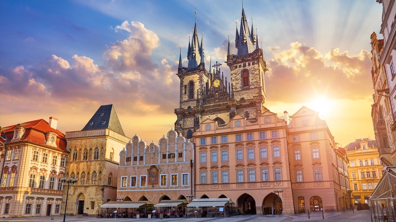 Sun rising behind Prague's historic Gothic cathedral overlooking Old Town Square