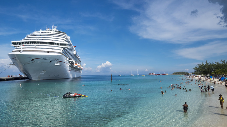 Cruise ship in the Caribbean, near a coastline with swimmers standing in the water